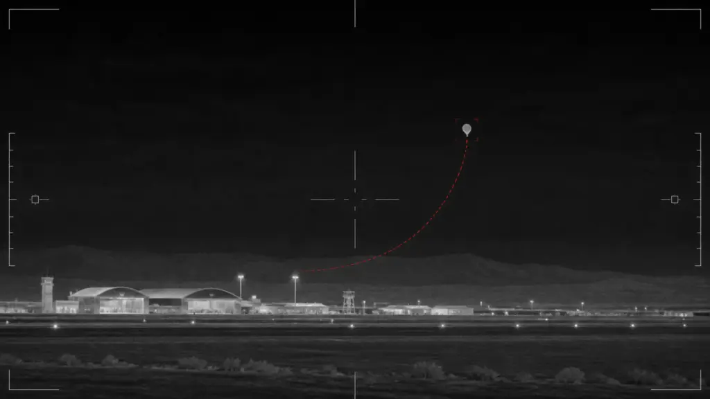 Editorial thermal-sensor illustration of a balloon-like object above Al Taqaddum airbase